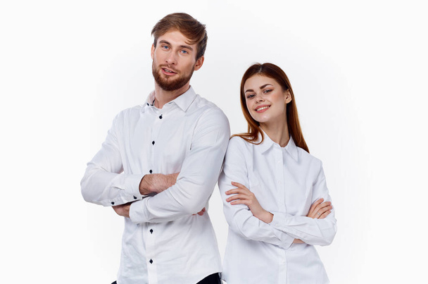 Μια γυναίκα και ένας άντρας με άσπρα πουκάμισα στέκονται ο ένας δίπλα στον άλλο με τα χέρια σταυρωμένα στο στήθος. - Φωτογραφία, εικόνα
