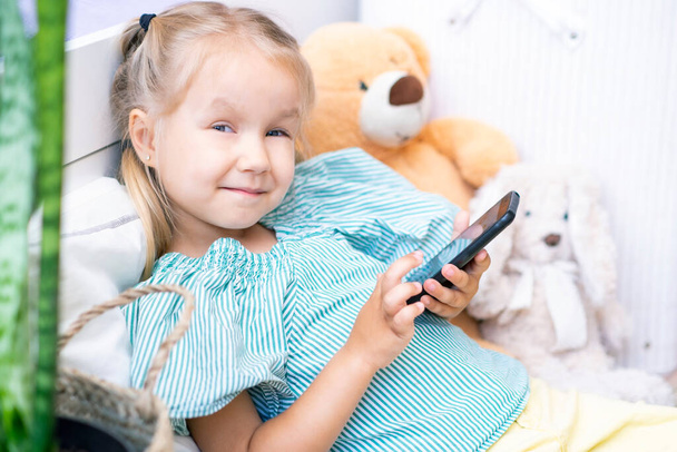 Happy girl with a smartphone in her hands at home. Smartphone games, video calls - Photo, Image