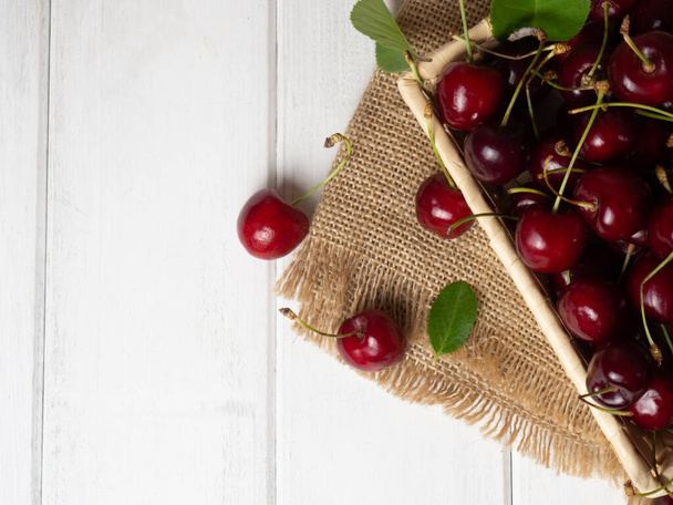fresh cherries in a wicker basket on a white wooden table - 写真・画像