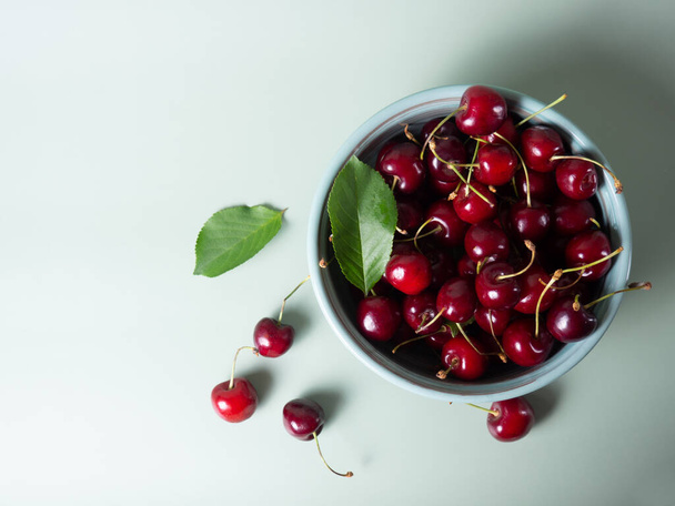 ripe cherries in a bowl on a menthol background with place for your text - Фото, изображение