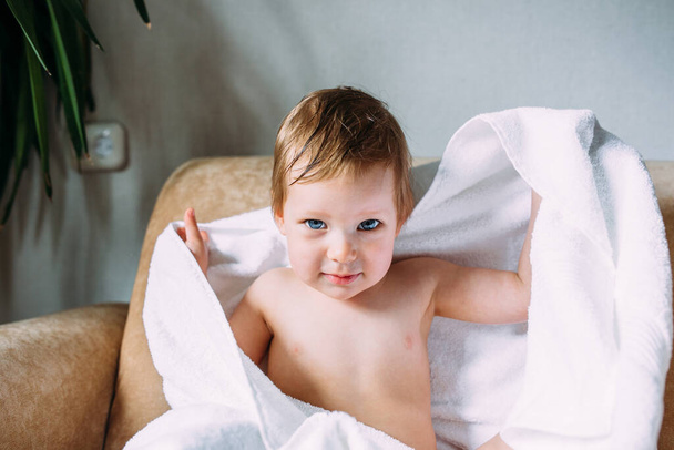 Cute child with blue eyes wrapped in a white towel.  - Фото, изображение
