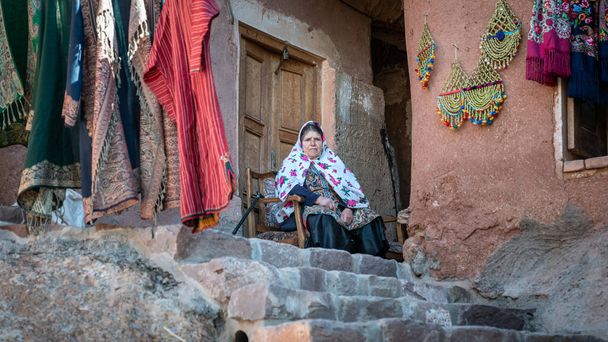 Abyaneh, Iran - May 2019: Iranian woman with traditional Abyaneh Persian dess sitting infront of her house in Abyahen, Iran - Fotoğraf, Görsel