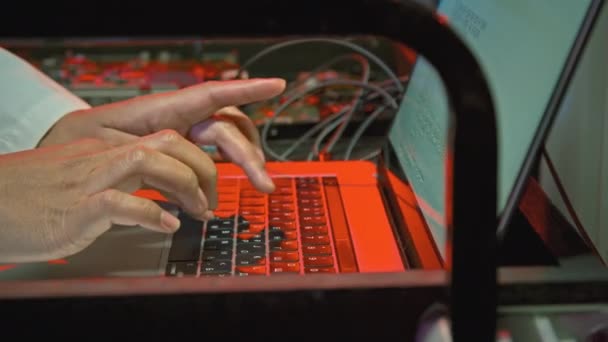 Close-up shot van onherkenbare mannelijke IT-specialist typen op laptop staan op dienblad of kar met apparatuur en kabels - Video