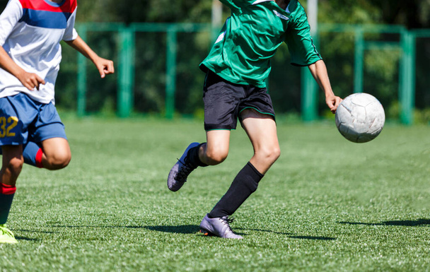 Sahada koşan yeşil giysili çocuklar. Genç futbolcular maçta top sürüp tekmeliyorlar. Eğitim, aktif yaşam tarzı, spor  - Fotoğraf, Görsel