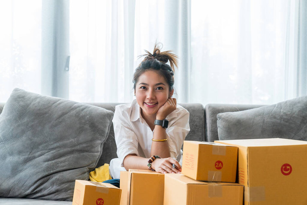 Mulheres asiáticas bonitas sentadas no sofá com muitas caixas de encomendas com pequenas empresas vendem ao cliente em compras on-line. Conceito venda e compras on-line a partir de casa - Foto, Imagem