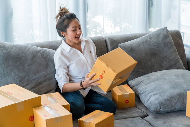 Gyönyörű ázsiai nők ülnek a kanapén sok csomag doboz kisvállalkozások eladni az ügyfélnek az online vásárlás. Concept értékesítés és vásárlás online otthonról - Fotó, kép