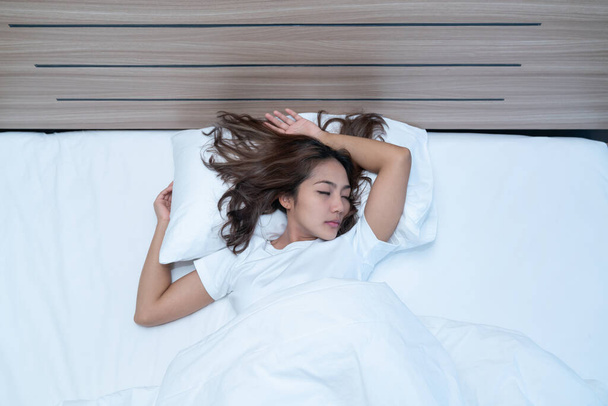 Top uitzicht op mooie jonge vrouw slapen gezellig op een bed in zijn slaapkamer 's nachts. - Foto, afbeelding
