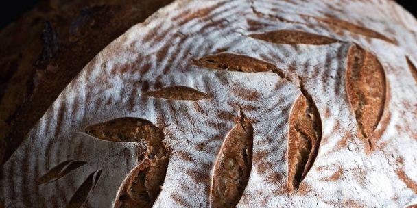 Homemade round dark bread with flour crust and painted spikelet close up on - Fotoğraf, Görsel
