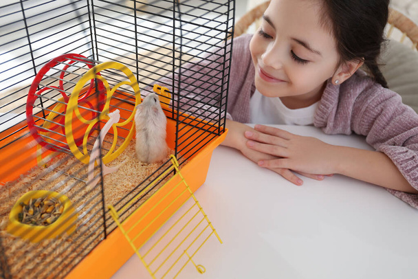Little girl and her hamster in cage at home - Foto, immagini
