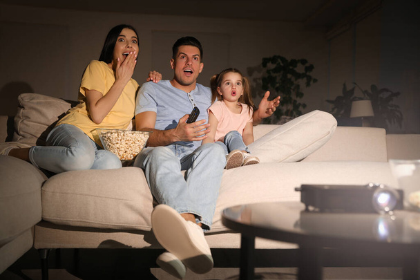 Family watching movie with popcorn on sofa at night - Fotografie, Obrázek