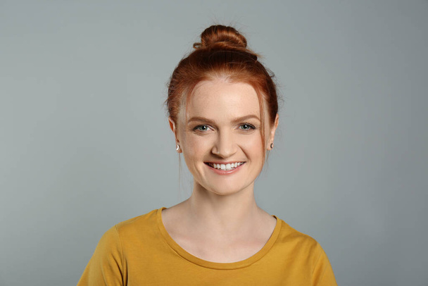 Candid portrait of happy red haired woman with charming smile on grey background - Valokuva, kuva