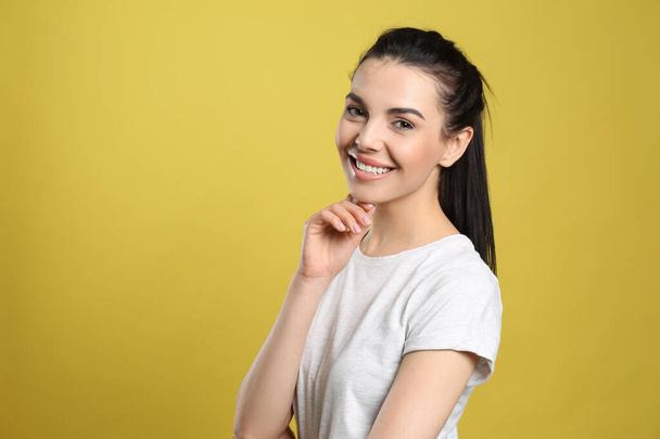 Portrait of happy young woman with beautiful black hair and charming smile on yellow background, space for text - Foto, Bild