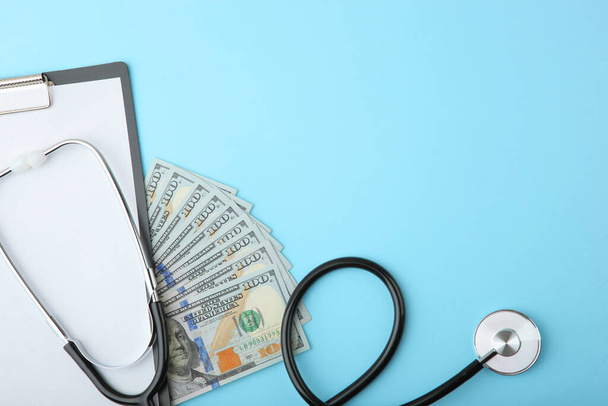 Медичний стетоскоп і гроші на кольоровому фоні вид зверху крупним планом
 - Фото, зображення