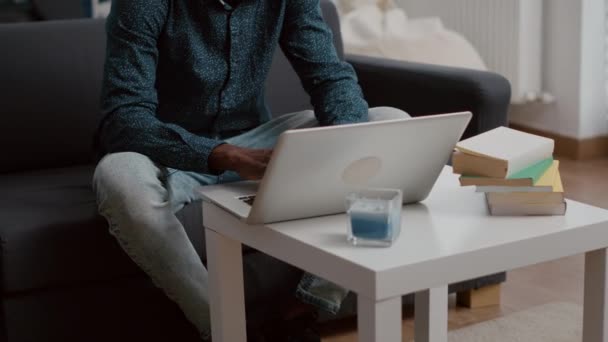 Eredeti mosolygós fekete afro-amerikai srác dolgozik otthonról a laptopján - Felvétel, videó