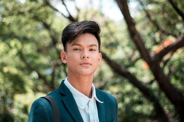 Un bel e giovane studente universitario filippino in abbigliamento casual intelligente. Uno sguardo serio. Nel parco o nel campus. - Foto, immagini