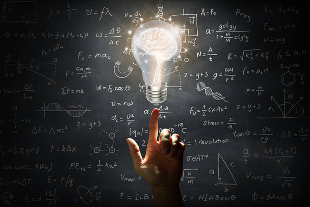 Mão segurando um cérebro dentro de uma lâmpada na parede backboard ou chalkboard fundo. Ideia brilhante de negócios, ótima ideia para o sucesso e conceito de mídia mista. - Foto, Imagem