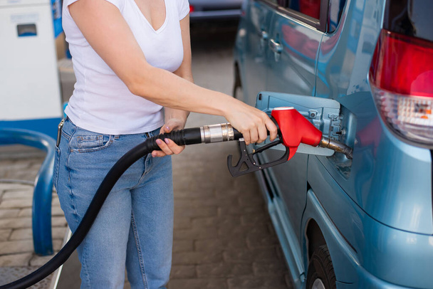 Woman refueling car with gasoline at self-service gas station. - Zdjęcie, obraz