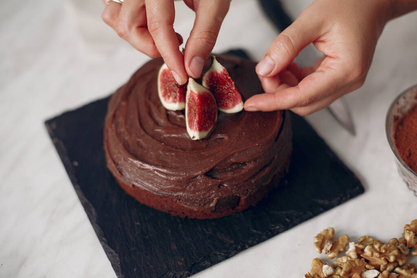 Confectioner decorates a chocolate cake with figs. - Valokuva, kuva