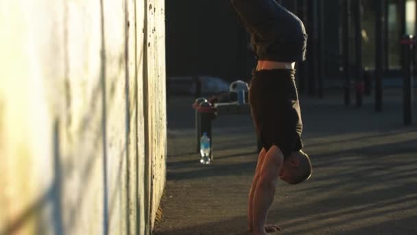 Молодий спортивний хлопець тримає своє тіло догори дном до стіни
 - Кадри, відео