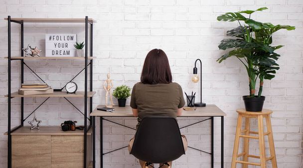 Back view of brunette woman sitting in bright interior - Photo, Image