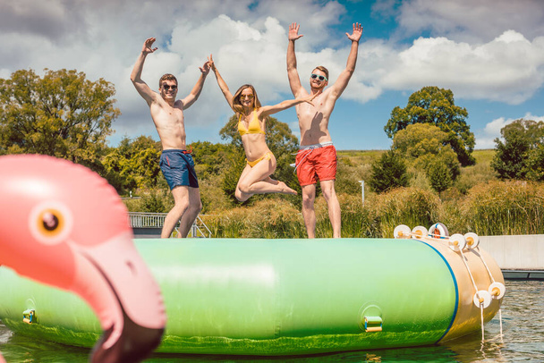 Amigos divirtiéndose saltando de una cosa tuby en la piscina pública - Foto, imagen