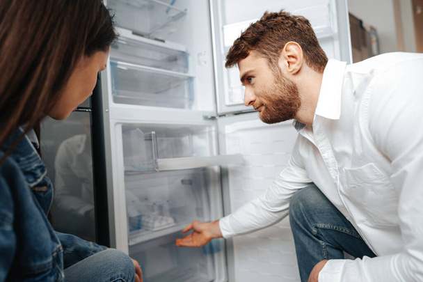 Young couple selecting new refrigerator in household appliance store - Φωτογραφία, εικόνα