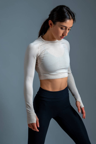 Relaxed athletic girl in sportswear standing on grey background - Photo, Image