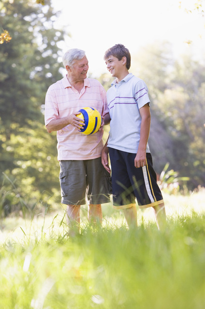 Grandfather and grandson at a park holding a ball and smiling - Fotoğraf, Görsel