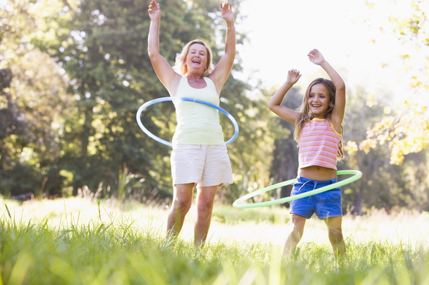 Grandmother and granddaughter at a park hula hooping and smiling - Fotografie, Obrázek