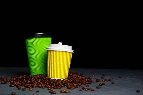 Closed take-out coffee with cup holder. Two yellow and green cups with coffee beans over black background. Copy space banner. Delivery or takeout concept. - Фото, зображення