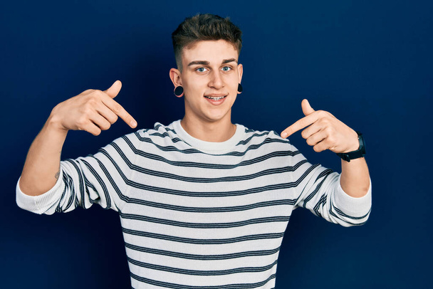 Young caucasian boy with ears dilation wearing casual striped shirt looking confident with smile on face, pointing oneself with fingers proud and happy.  - Photo, Image