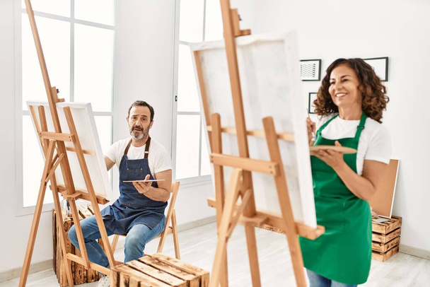Two middle age student smiling happy painting at art studio. - Photo, Image