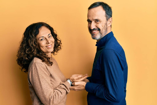 Middle age hispanic couple wearing casual clothes pointing aside with hands open palms showing copy space, presenting advertisement smiling excited happy  - Fotó, kép