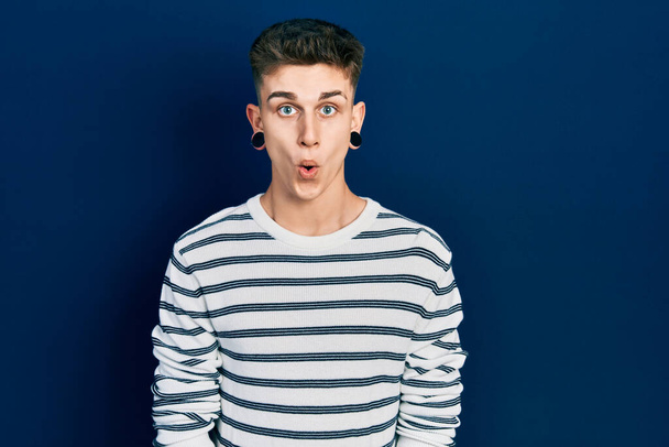 Young caucasian boy with ears dilation wearing casual striped shirt afraid and shocked with surprise expression, fear and excited face.  - Photo, Image