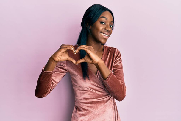 Fiatal afro-amerikai nő visel szexi party ruha mosolyog a szerelemben csinál szív szimbólum alakú kezekkel. romantikus koncepció.  - Fotó, kép