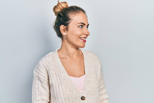 Junge kaukasische Frau in lässiger Kleidung, die zur Seite schaut, entspannte Profil-Pose mit natürlichem Gesicht und selbstbewusstem Lächeln.  - Foto, Bild