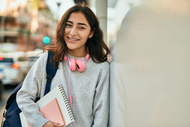 młody Bliski Wschód student dziewczyna uśmiechnięty szczęśliwy gospodarstwa książki w mieście. - Zdjęcie, obraz