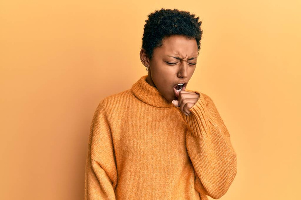 Jeune fille afro-américaine portant des vêtements décontractés se sentant mal et toussant comme symptôme de rhume ou de bronchite. concept de soins de santé.  - Photo, image