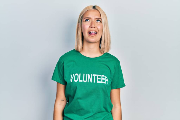 Beautiful blonde woman wearing volunteer t shirt angry and mad screaming frustrated and furious, shouting with anger. rage and aggressive concept.  - Photo, Image