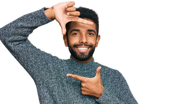 若いアフリカ系アメリカ人の男性が幸せな顔で手や指でフレームを作る笑顔カジュアルな服を着て.創造性と写真の概念.  - 写真・画像