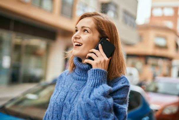 Молодая кавказская девушка улыбается счастливо разговаривая по смартфону в городе. - Фото, изображение