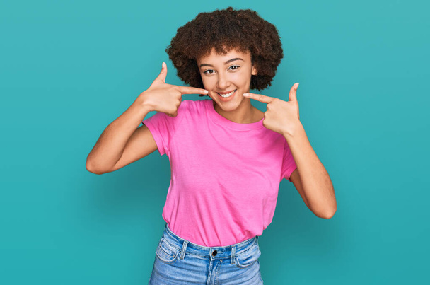 Young hispanic girl wearing casual clothes smiling cheerful showing and pointing with fingers teeth and mouth. dental health concept.  - Photo, Image