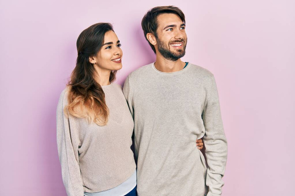 Молода пара іспаномовних в повсякденному одязі дивиться в сторону з посмішкою на обличчі, природним виразом. впевнений сміх
.  - Фото, зображення