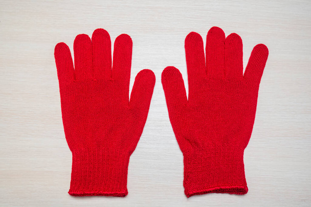 Ahşap ışıklı arka planda kırmızı iş eldivenleri. Bahçe için örülmüş iş eldivenleri, sebze bahçesi, kirli işler. - Fotoğraf, Görsel