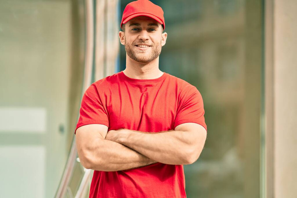 Young caucasian deliveryman smiling happy standing at the city. - Photo, Image