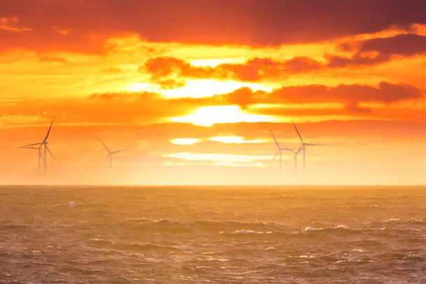 Açık denizde yenilenebilir yeşil elektrik rüzgar enerjisi üretimi. Karbonizasyon endüstrisinde gün doğumu rejeneratif enerjiler için yel değirmeni işi. Temiz enerji yenilenebilir kaynakları iklim değişikliğini önlemektedir. - Fotoğraf, Görsel