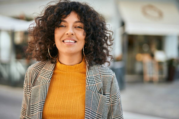 Jeune femme d'affaires hispanique souriant heureux debout à la ville. - Photo, image
