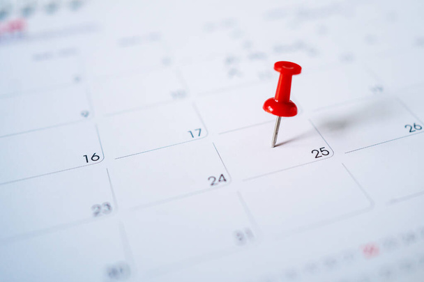 Selectieve focus. Foto van een kalender met een rode pin op de 25e. - Foto, afbeelding
