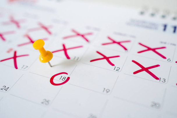 Calendario con alfileres amarillos el día 18. Los alfileres amarillos son las fechas del calendario o planificador. - Foto, Imagen