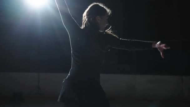Slow motion: Cinematic shot of young female artistic figure skater is performing a womans single skating choreography on ice rink before start of a competition. Concept of freedom - Footage, Video